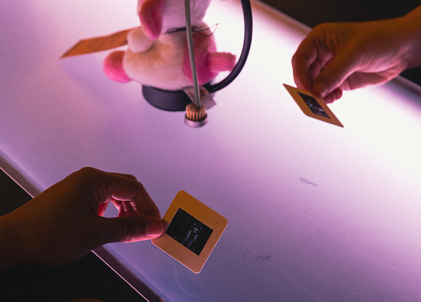 Two people examine images on slides over a softly lit table